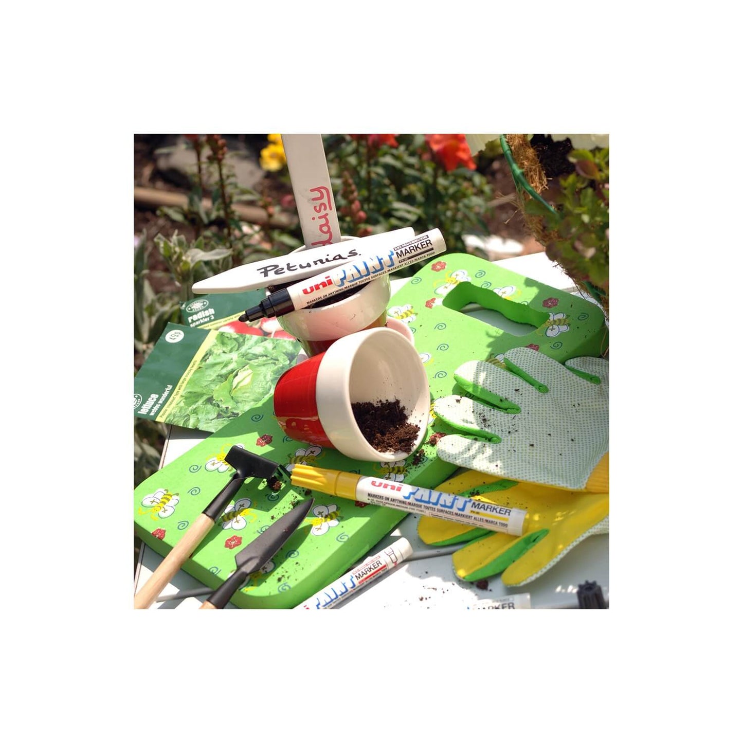 Gardening tools and supplies including a cup, uni-ball markers, and gloves on a white background.
