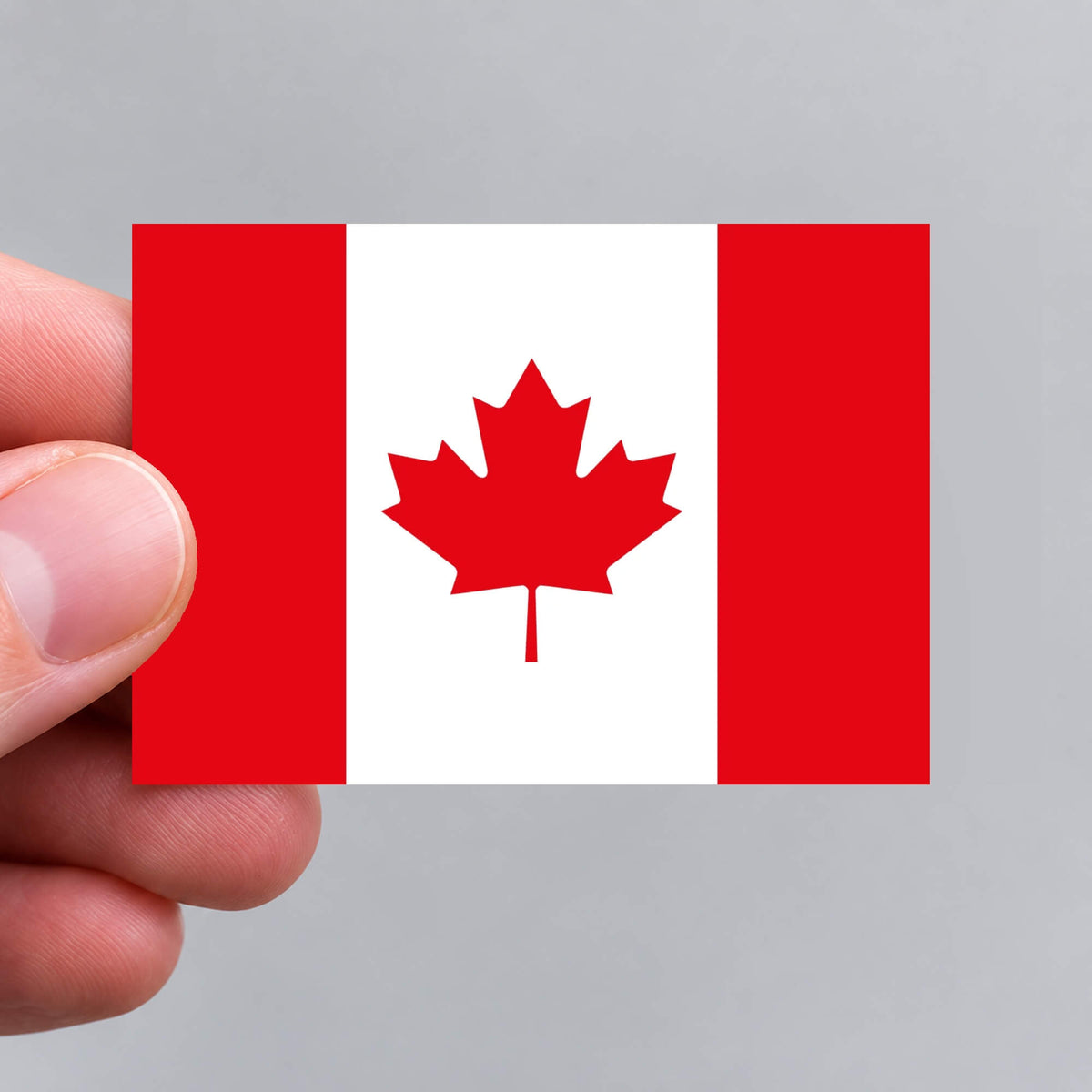 A hand holding a Canadian flag sticker by Gobrecht & Ulrich