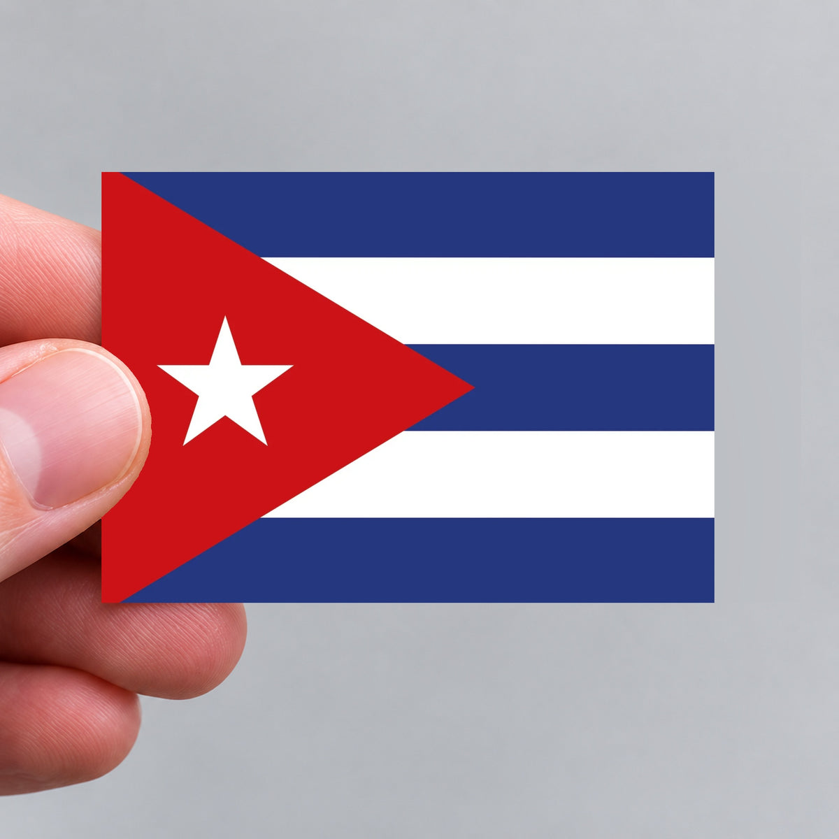 A hand holding a flag of Cuba sticker
