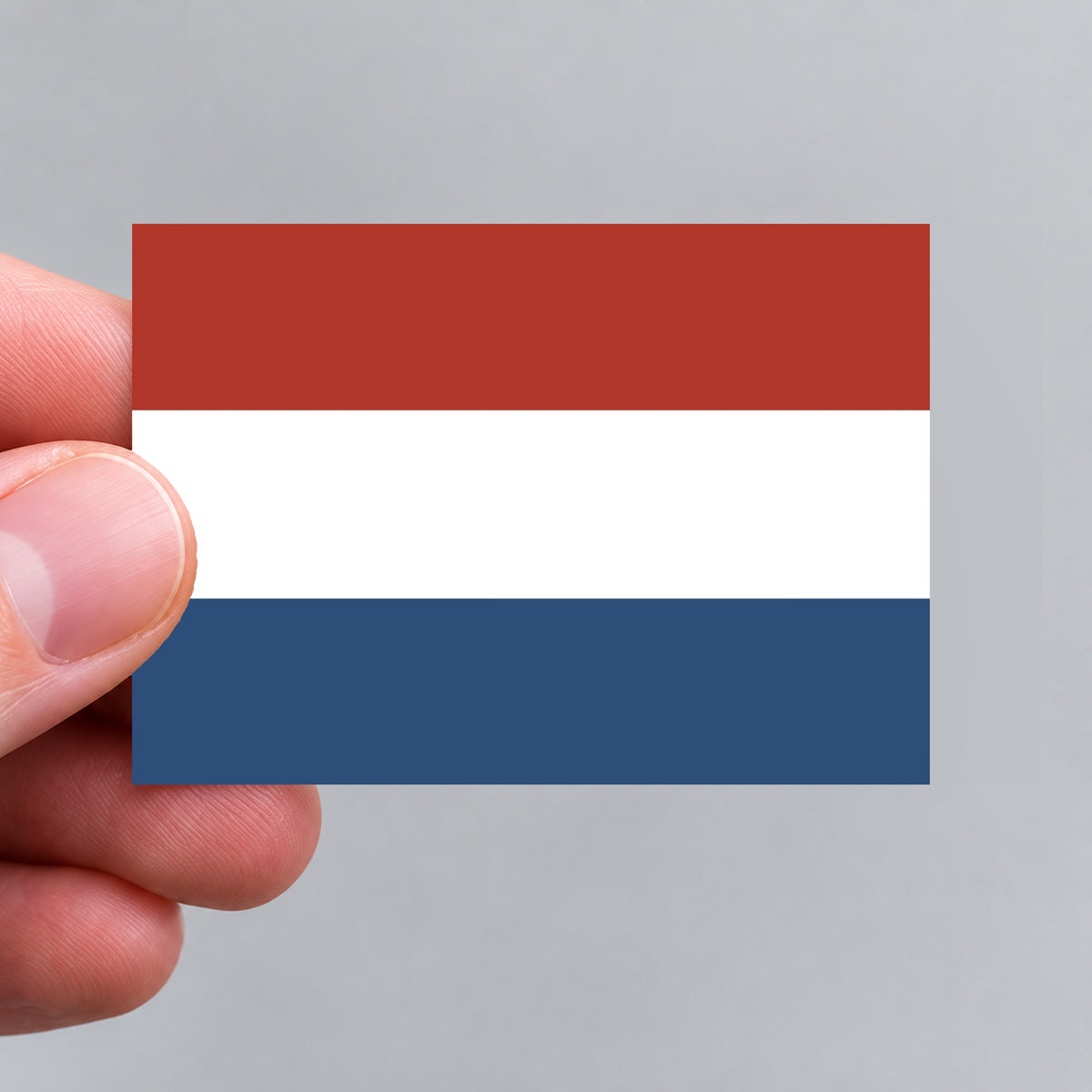 A hand holding a Dutch flag sticker