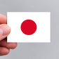A hand holding a Japanese flag sticker