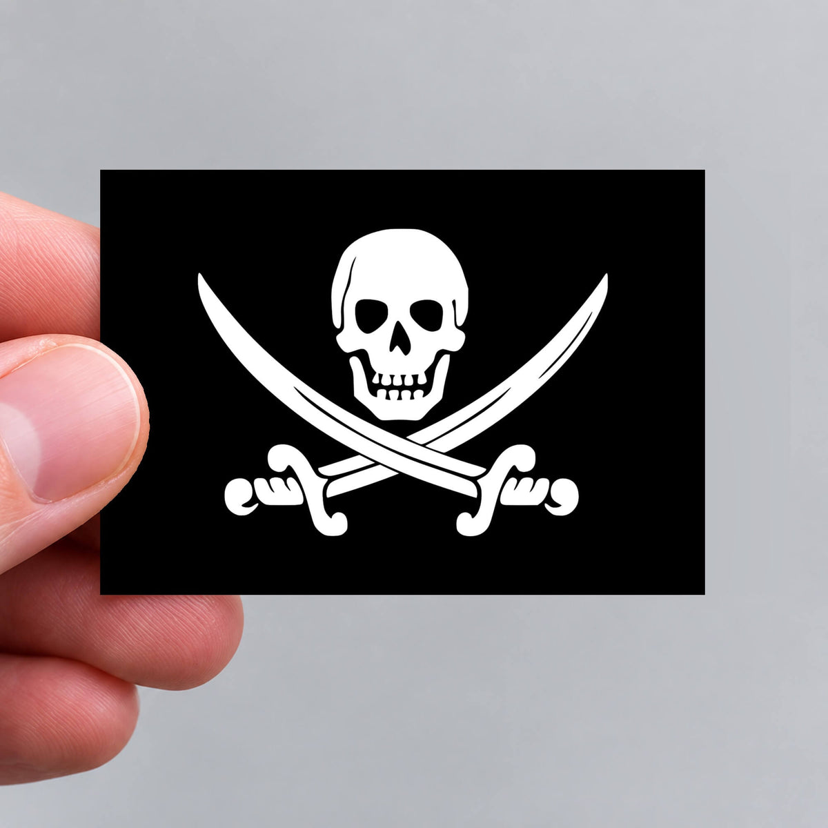 A hand holding a Jolly Roger pirate flag sticker by Gobrecht & Ulrich