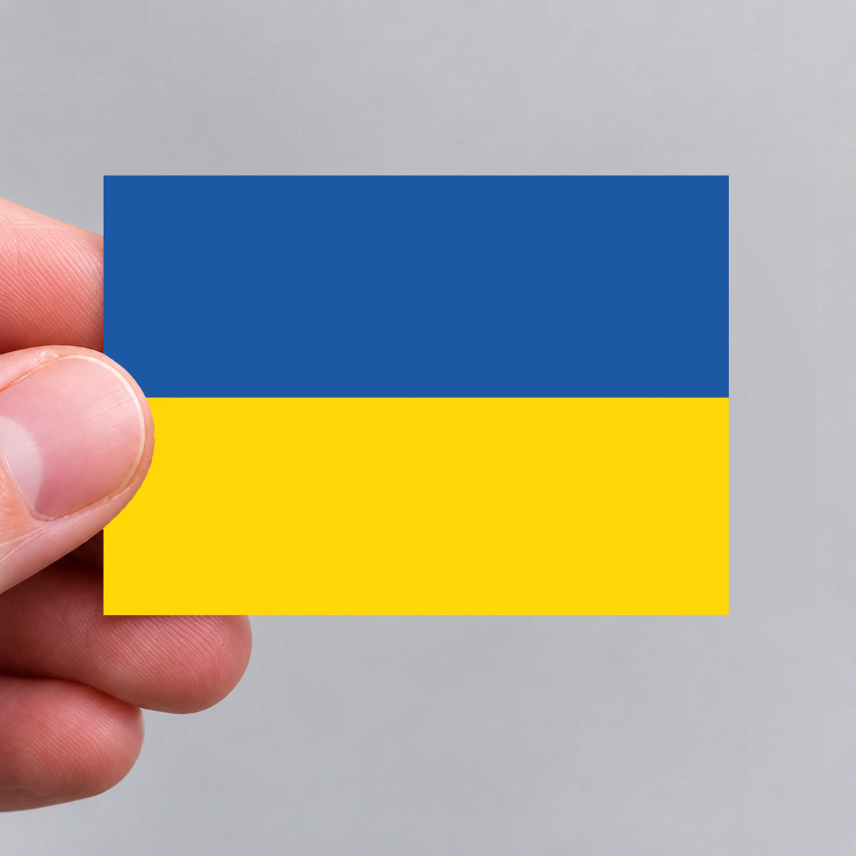 A hand holding a Ukrainian flag sticker by Gobrecht & Ulrich