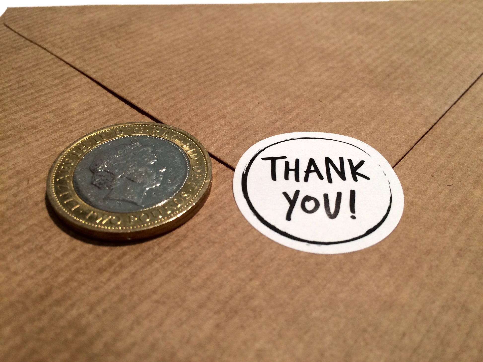 Size comparison thank you sticker and £2 coin